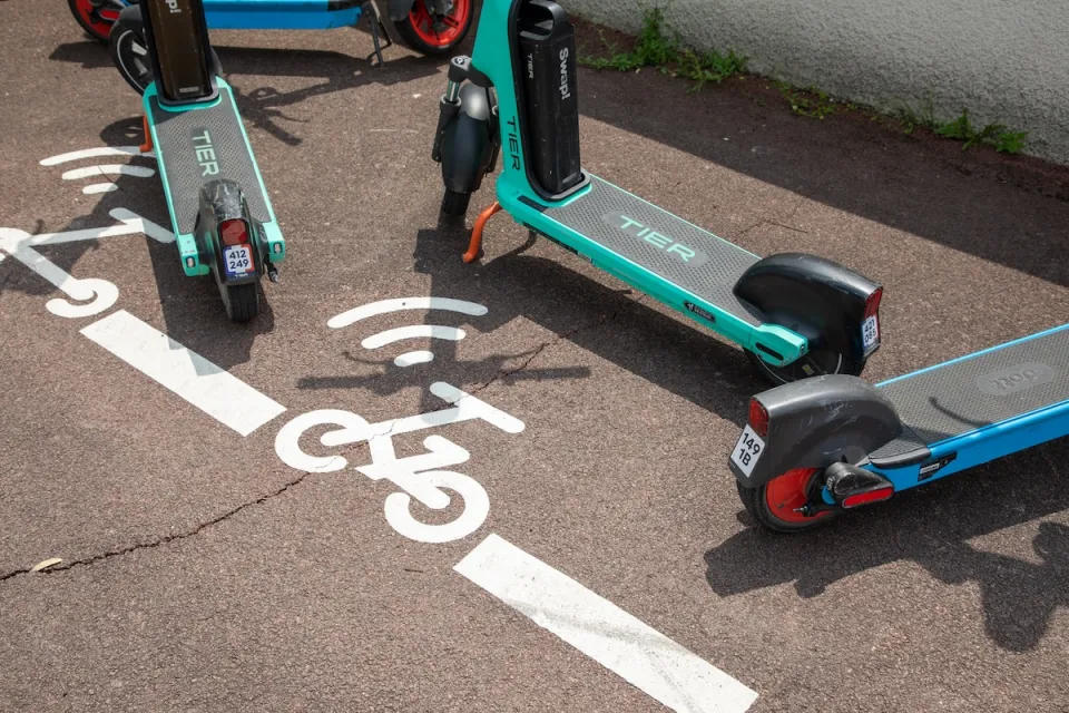 Close-up on e-scooters parked in painted designated parking area on city street.